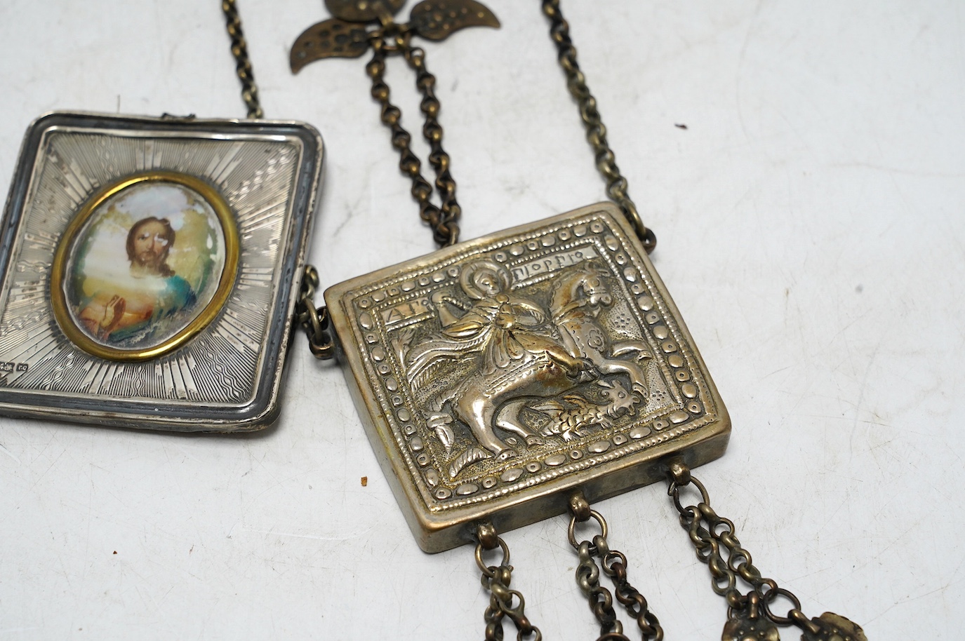 A Greek white metal pendant, embossed with St. George and the dragon, on a chain and a Russian white metal framed portrait of Christ. Condition - poor to fair